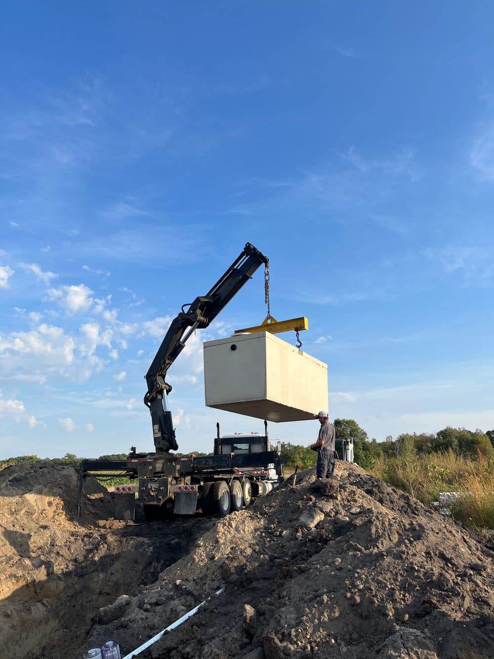 Crane lifting a large container at a construction site under a clear blue sky.