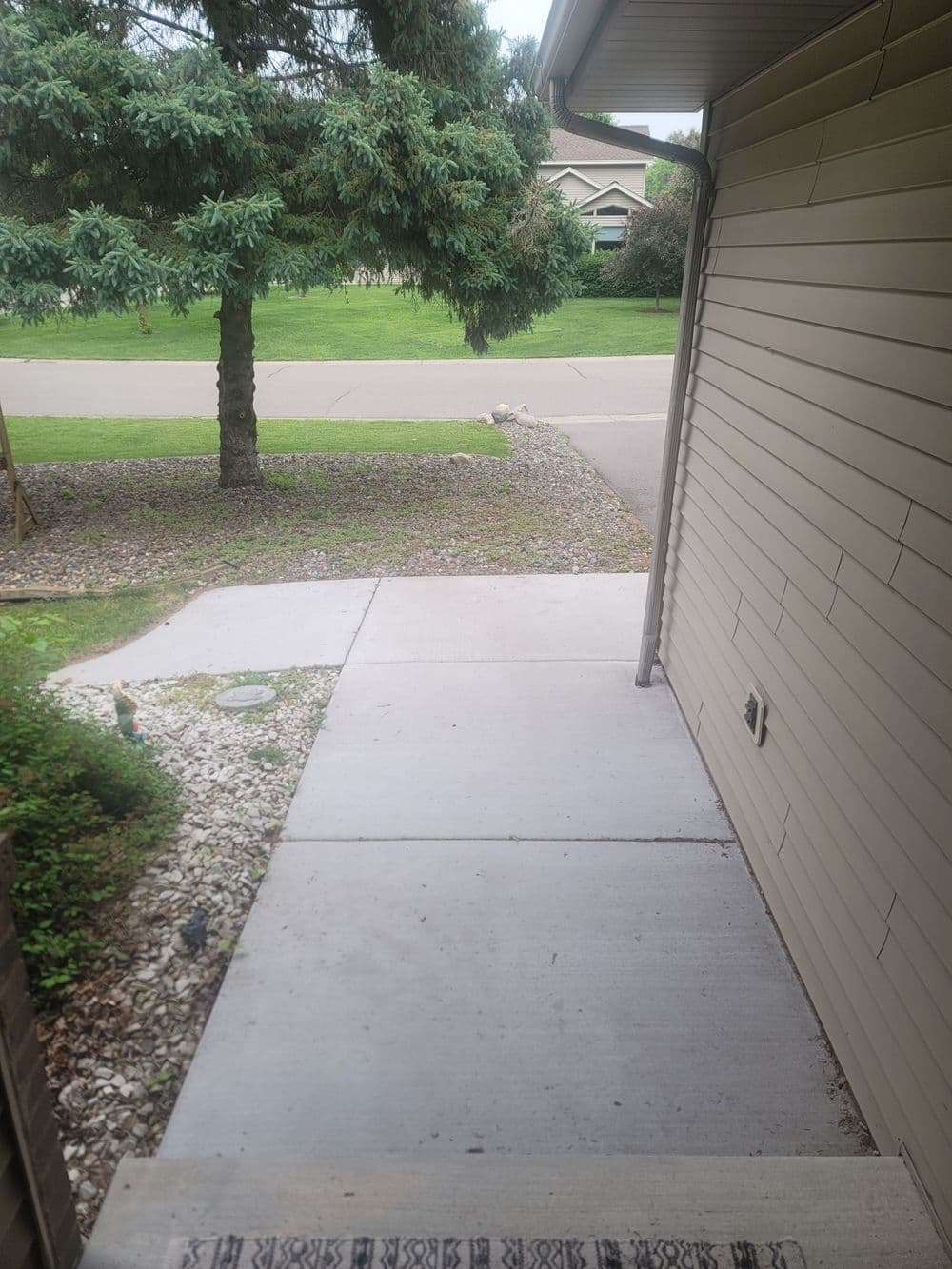 View from porch showing sidewalk, lawn, and trees on a quiet suburban street.