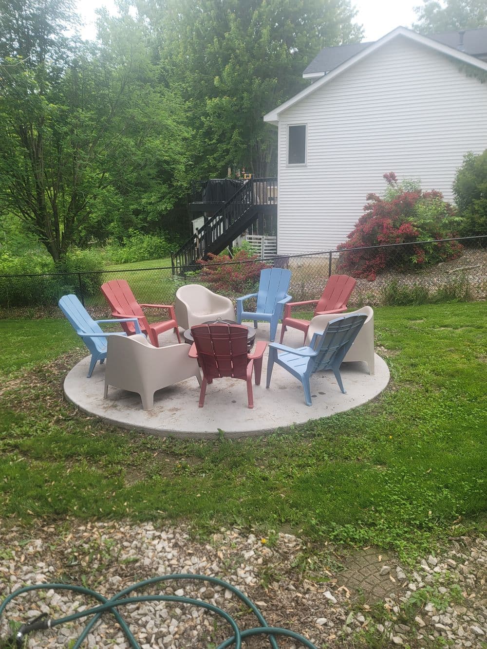 Colorful outdoor chairs arranged in a circle on a patio surrounded by green foliage.