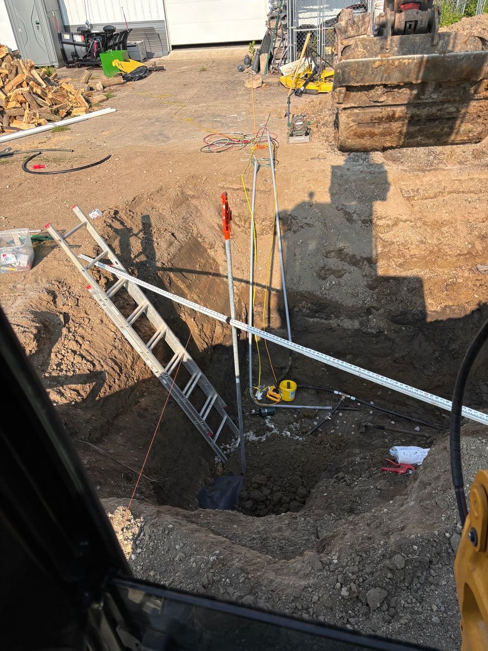 Construction site showing a deep excavation with ladders and safety equipment.